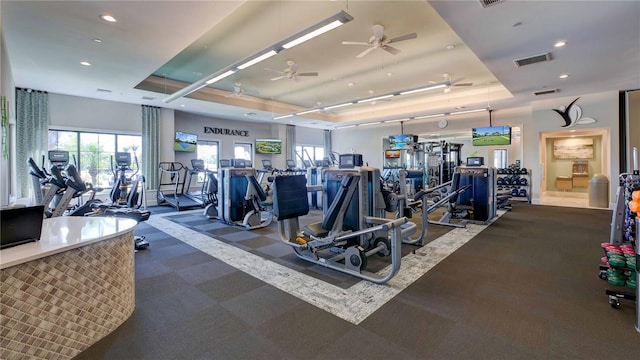 gym with ceiling fan and a raised ceiling