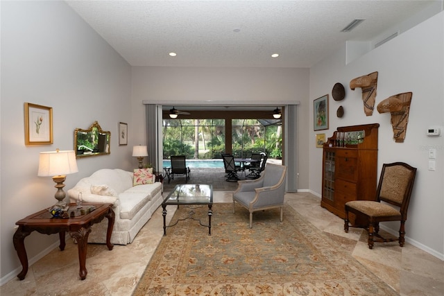 living room featuring ceiling fan and a textured ceiling