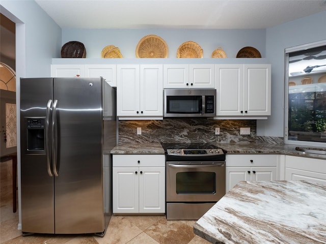 kitchen with dark stone counters, white cabinetry, and appliances with stainless steel finishes