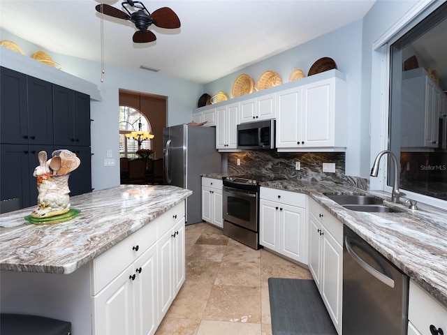 kitchen with stainless steel appliances, white cabinets, decorative backsplash, sink, and ceiling fan