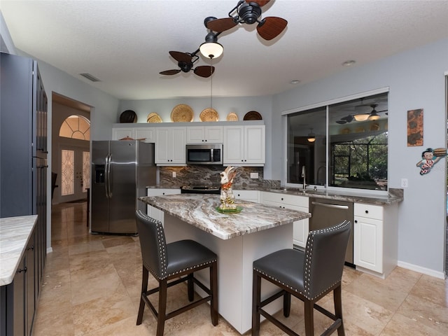 kitchen featuring a kitchen island, white cabinetry, and appliances with stainless steel finishes