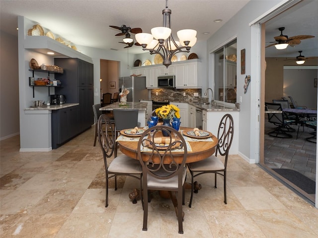 dining space with ceiling fan with notable chandelier and sink