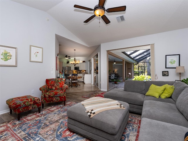 living room with dark wood-type flooring, ceiling fan with notable chandelier, and vaulted ceiling