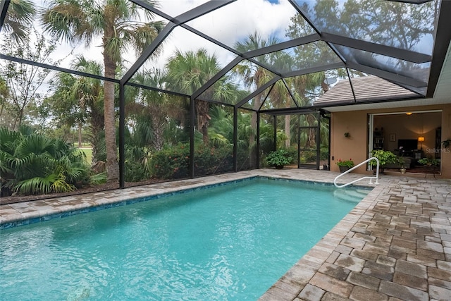 view of pool with glass enclosure and a patio