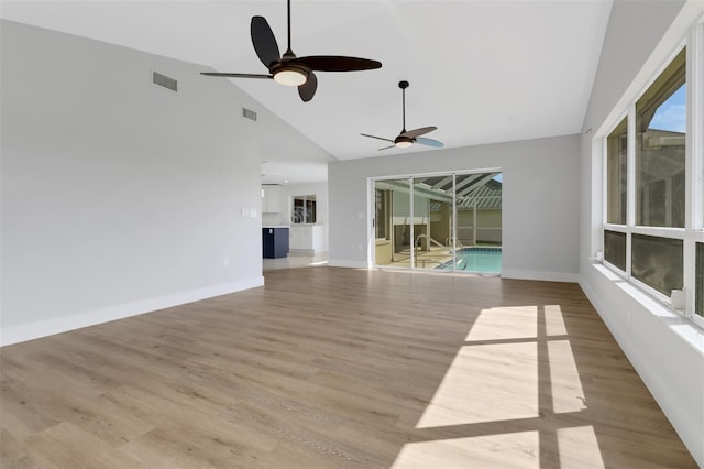 unfurnished living room with light hardwood / wood-style floors, ceiling fan, and high vaulted ceiling