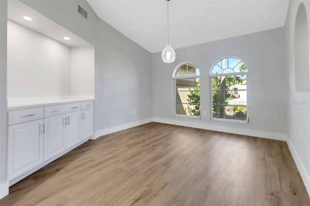 unfurnished dining area featuring light hardwood / wood-style flooring and lofted ceiling