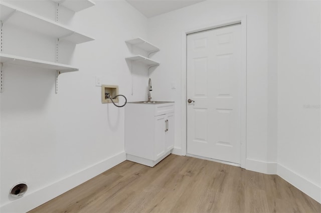 laundry area featuring hookup for a washing machine, cabinets, and light hardwood / wood-style flooring