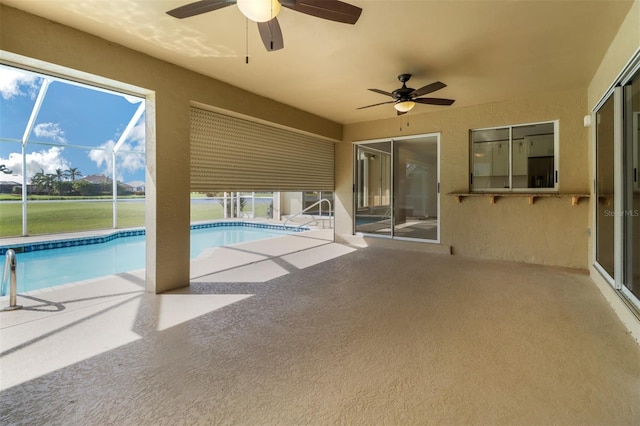 view of swimming pool featuring ceiling fan, glass enclosure, and a patio