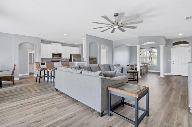 living room featuring light hardwood / wood-style floors, ornate columns, and ceiling fan