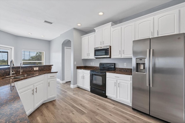 kitchen featuring sink, light hardwood / wood-style floors, stainless steel appliances, dark stone counters, and white cabinets