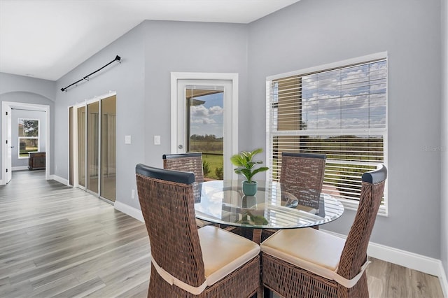 dining space featuring lofted ceiling, light hardwood / wood-style flooring, and plenty of natural light