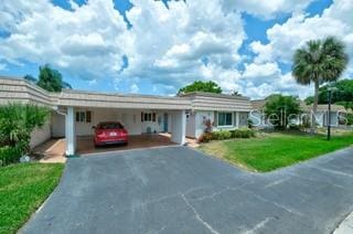 ranch-style home featuring a carport and a front yard