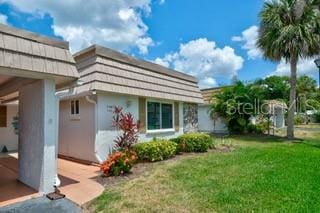 2609 Riverbluff Pkwy Unit 146, Sarasota, FL 34231 - view of side of home featuring stucco siding, a lawn, and mansard roof