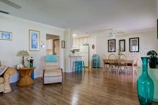 living room featuring dark wood-type flooring, crown molding, and ceiling fan