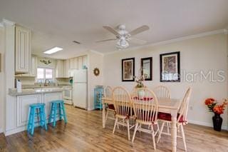 dining room featuring light hardwood / wood-style floors, ornamental molding, and ceiling fan