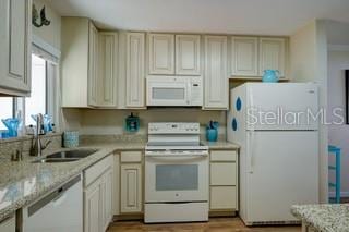 kitchen featuring white appliances, cream cabinets, sink, light stone countertops, and light hardwood / wood-style flooring