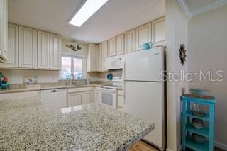 kitchen with white appliances, light stone counters, ornamental molding, and cream cabinets