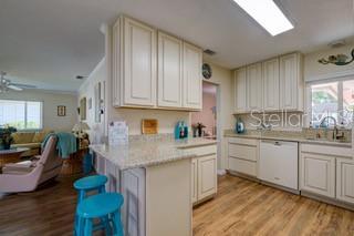2609 Riverbluff Pkwy Unit 146, Sarasota, FL 34231 - kitchen featuring white dishwasher, a sink, light wood-type flooring, open floor plan, and light countertops