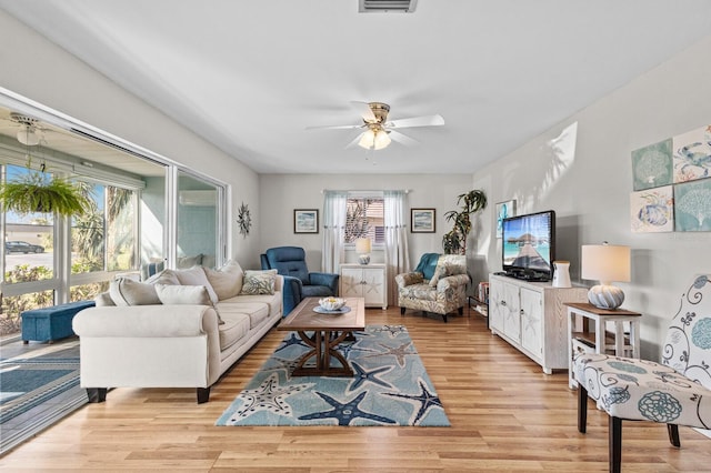 living room featuring light wood-type flooring, ceiling fan, and plenty of natural light