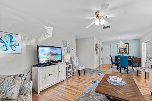 living room featuring ceiling fan with notable chandelier and light hardwood / wood-style flooring