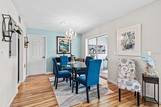 dining area with light hardwood / wood-style floors and an inviting chandelier