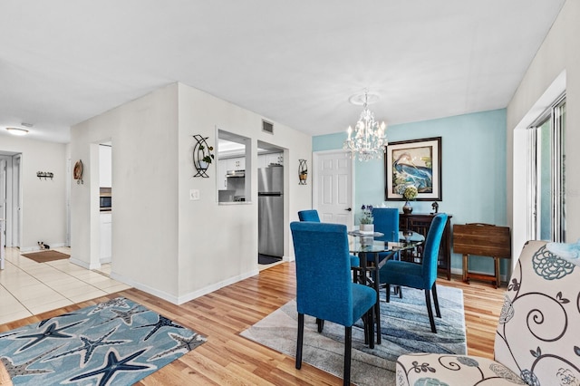 dining area featuring light hardwood / wood-style floors and a chandelier