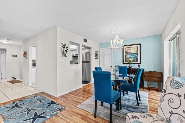 dining space with a notable chandelier and light hardwood / wood-style floors