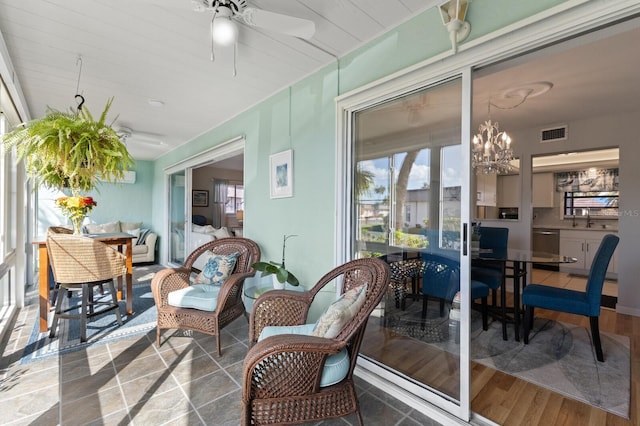 sunroom with ceiling fan with notable chandelier and sink