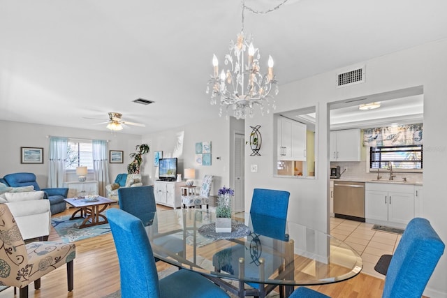 dining room with light hardwood / wood-style floors, ceiling fan with notable chandelier, and sink