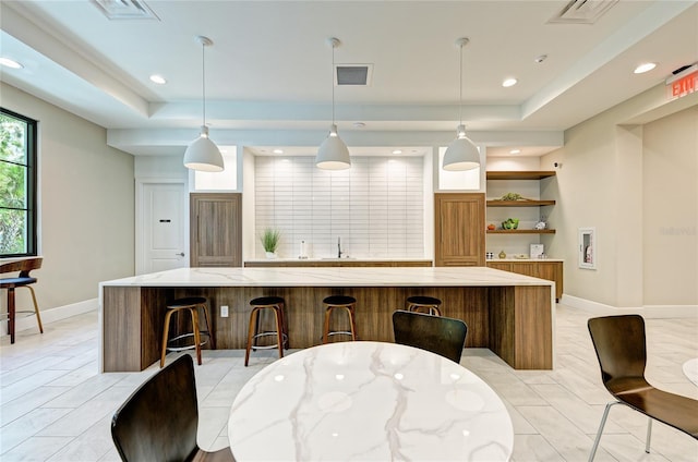 kitchen with a spacious island, visible vents, and a raised ceiling