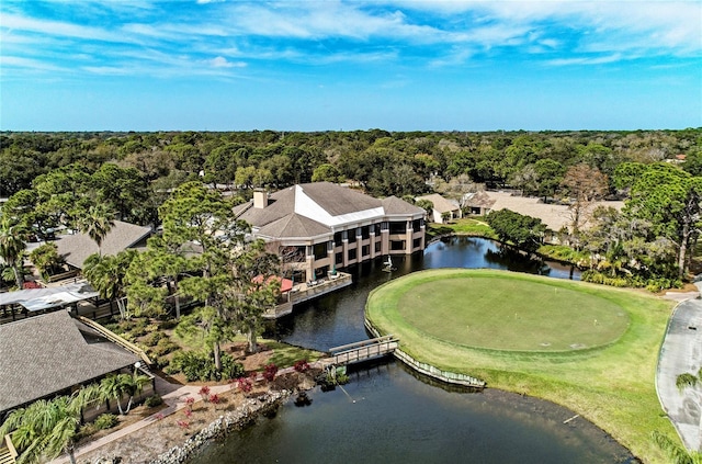 drone / aerial view with a view of trees, view of golf course, and a water view