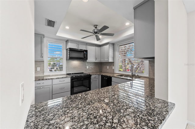 kitchen featuring tasteful backsplash, visible vents, black appliances, a raised ceiling, and a sink