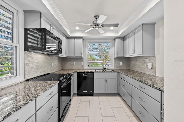 kitchen with black appliances, crown molding, a tray ceiling, and a sink