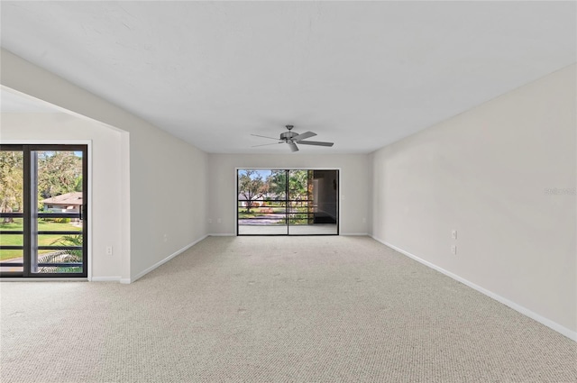 carpeted empty room with a ceiling fan, a healthy amount of sunlight, and baseboards