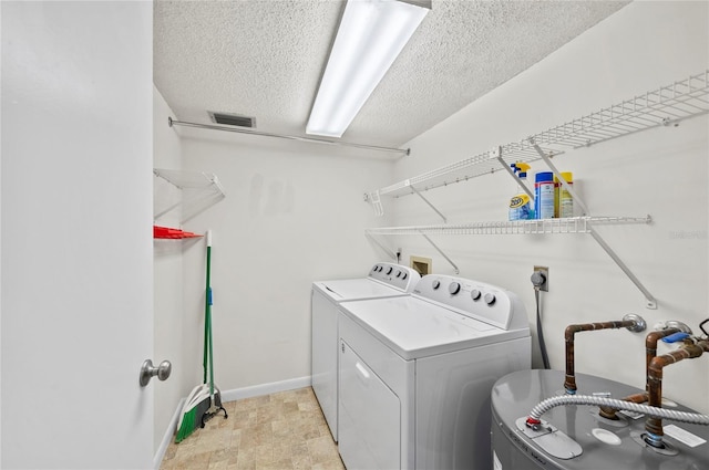 laundry area with washing machine and clothes dryer, visible vents, baseboards, laundry area, and a textured ceiling