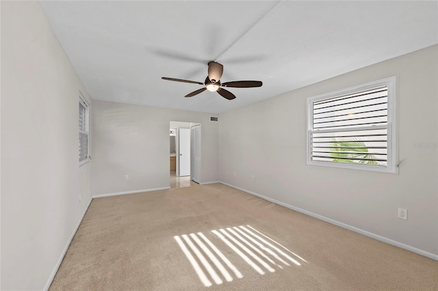 carpeted spare room with visible vents, baseboards, and a ceiling fan