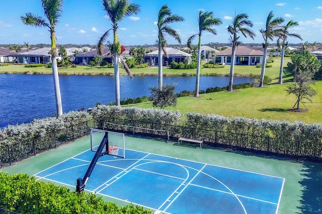 view of sport court with a water view and a yard