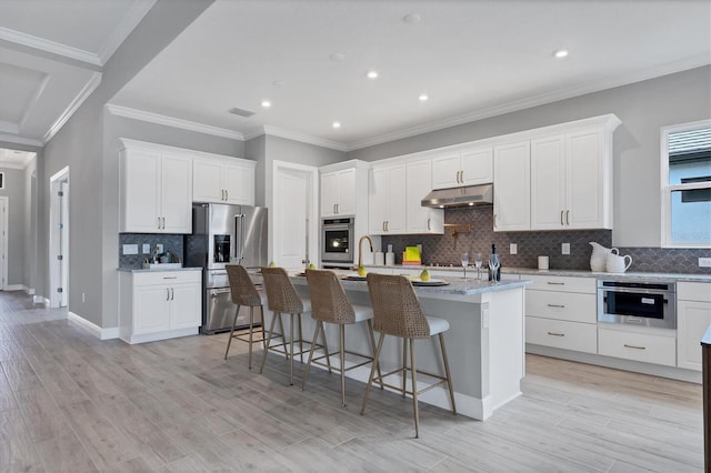 kitchen with white cabinetry, stainless steel appliances, an island with sink, and a breakfast bar area