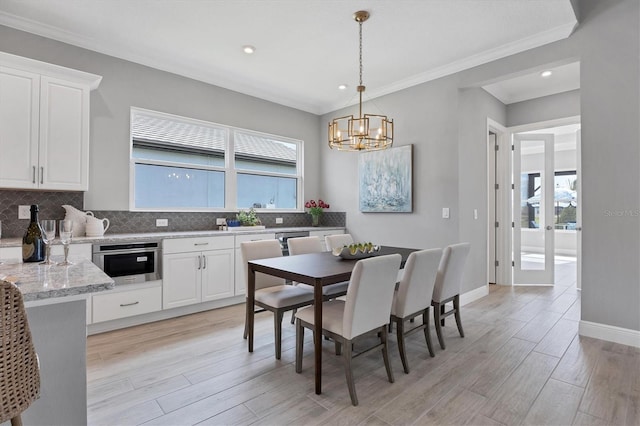 dining room featuring an inviting chandelier, ornamental molding, and light wood-type flooring