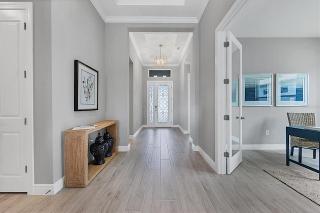 foyer featuring an inviting chandelier, ornamental molding, french doors, and light wood-type flooring