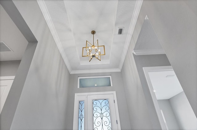 foyer with crown molding and an inviting chandelier