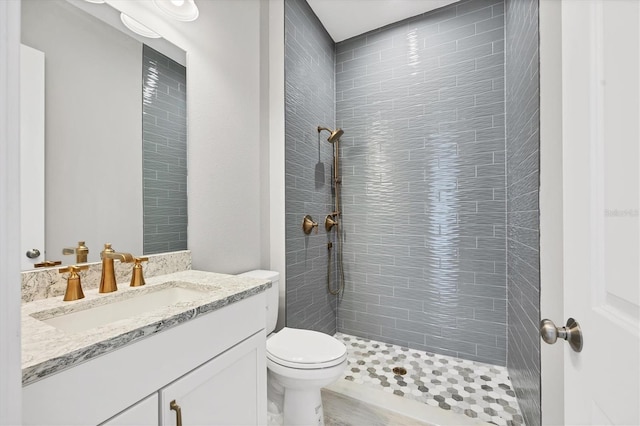 bathroom with vanity, toilet, and tiled shower