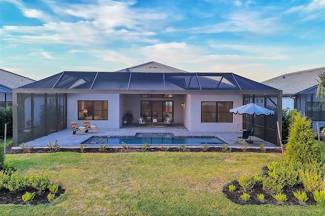 rear view of property featuring a lawn, glass enclosure, and a patio area