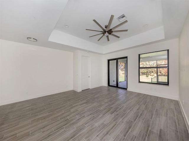 empty room featuring light hardwood / wood-style flooring, ceiling fan, and a raised ceiling