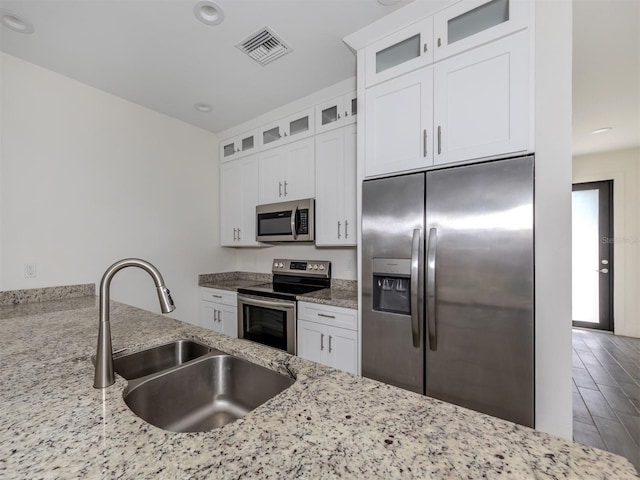 kitchen with sink, appliances with stainless steel finishes, light stone counters, and white cabinetry