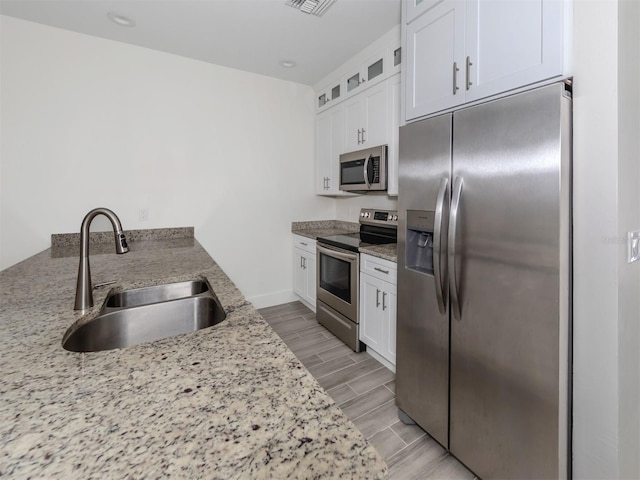 kitchen featuring light stone countertops, sink, white cabinets, and stainless steel appliances