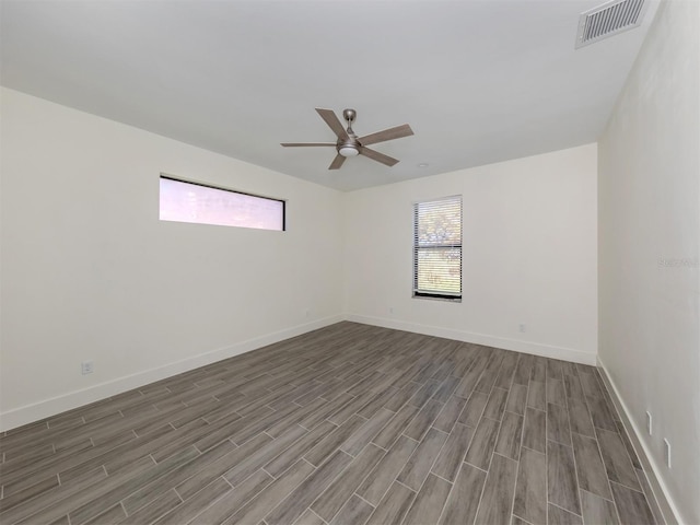 empty room with ceiling fan, a wealth of natural light, and hardwood / wood-style floors