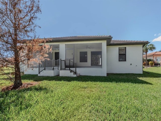 rear view of property featuring ceiling fan and a lawn