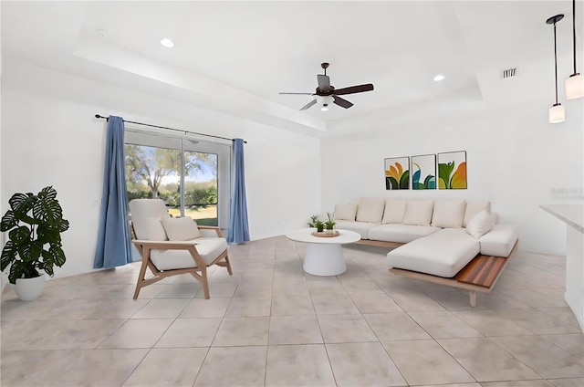 tiled living room featuring a raised ceiling and ceiling fan