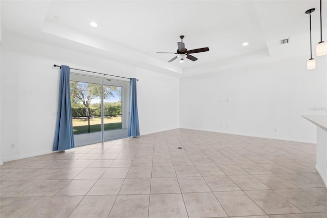 spare room with a raised ceiling, ceiling fan, and light tile patterned floors